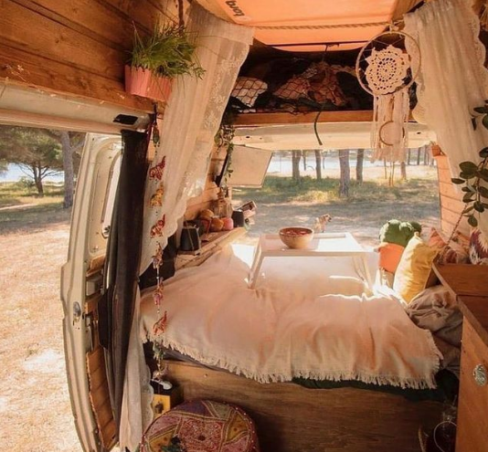 a campervan block bed decorated with white cushions and blankets