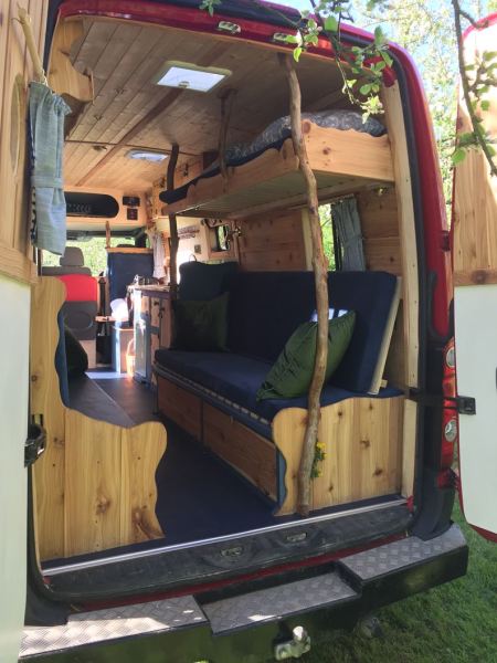 the back of a campervan is open revealing wooden bunkbeds