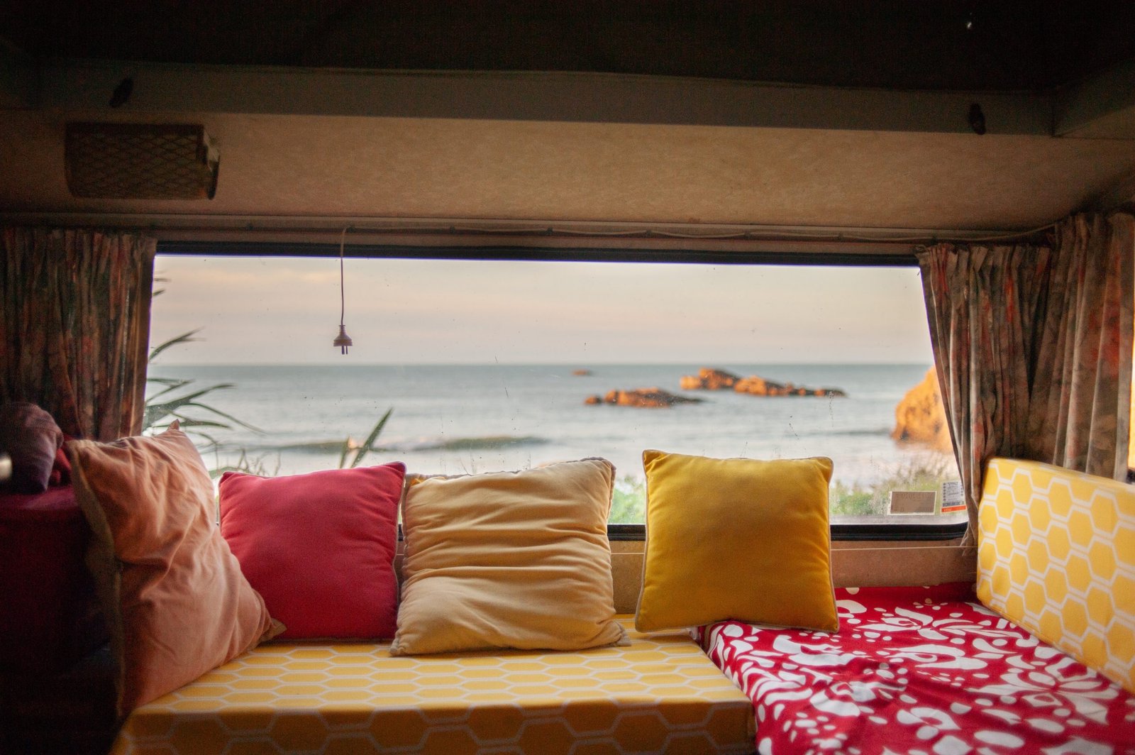 a view from a camper window with brightly coloured cushions 