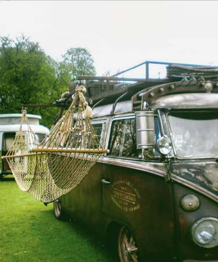 a vintage dark green campervan with a net hammock attached to the side