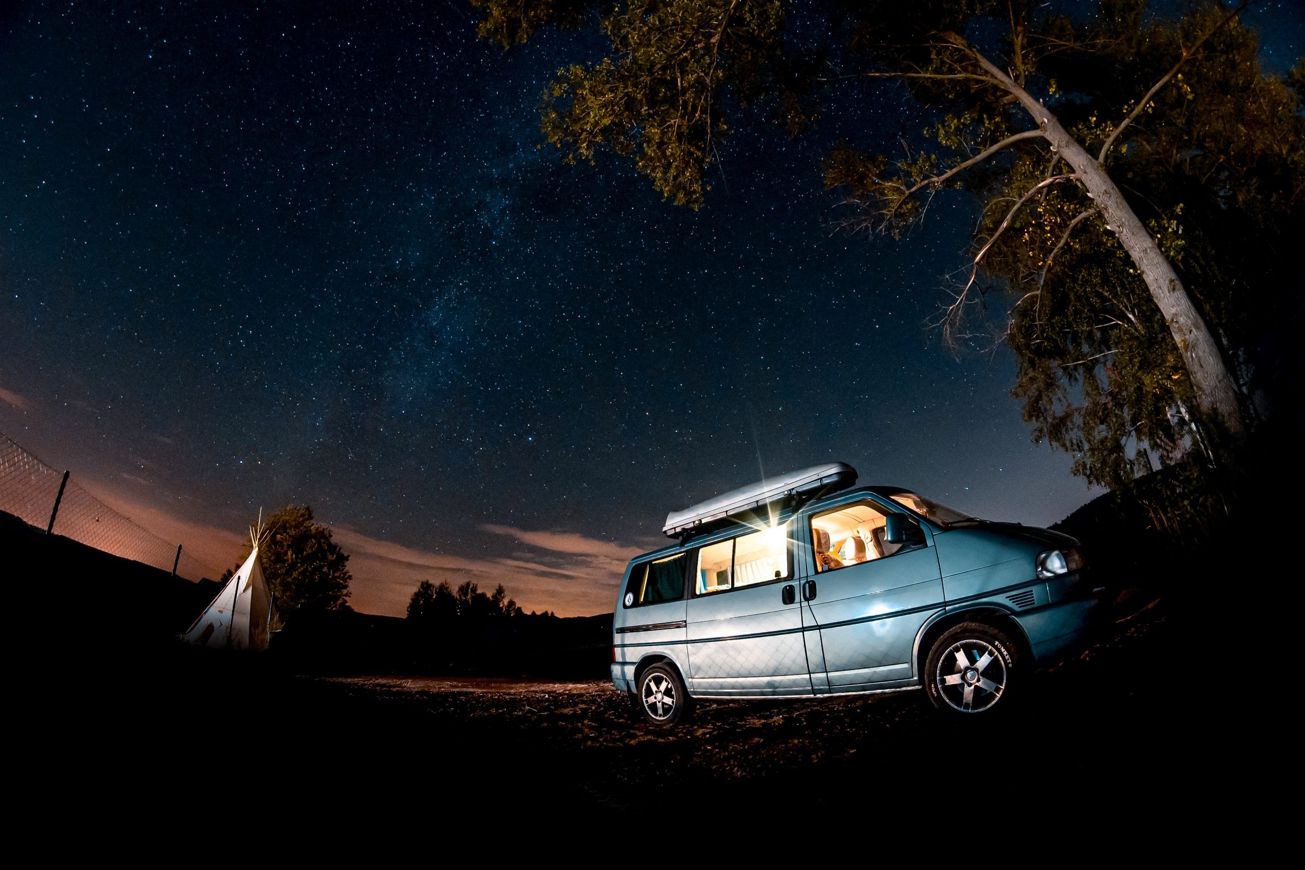 a blue campervan parked under the night sky