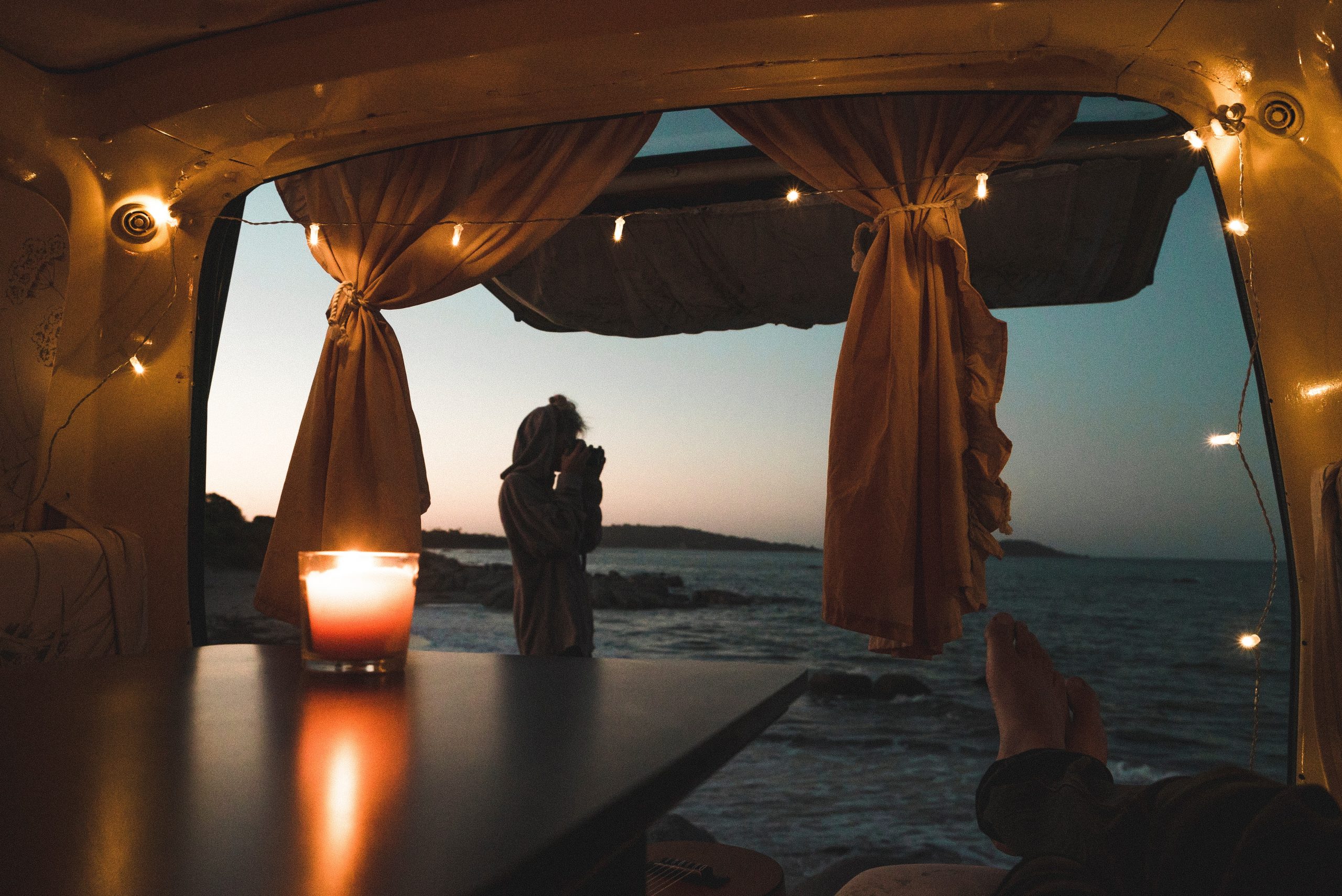 the view from the back of a converted campervan in the early evening with fairylights