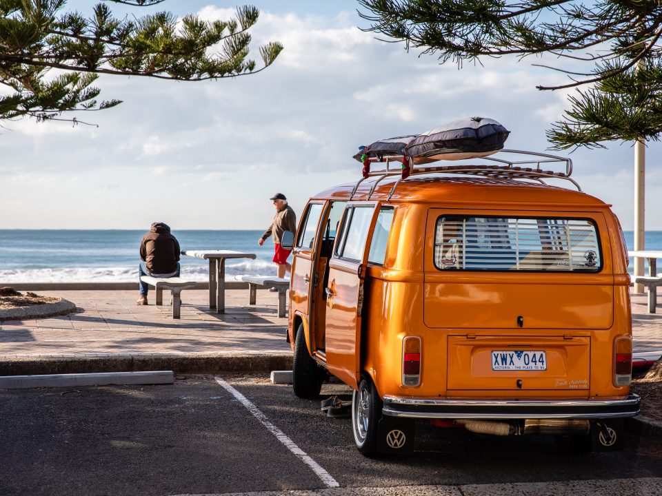 an orange campervan overlooks a beach scene