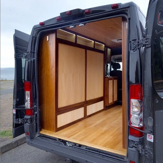 a campervan with the back doors open and wall beds