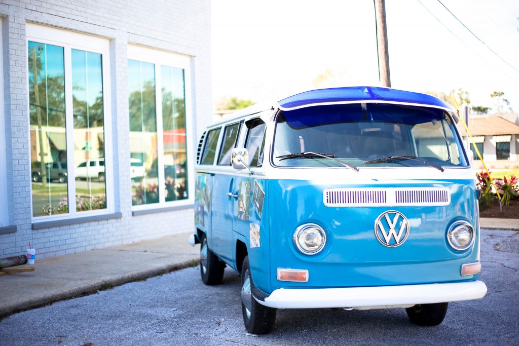 a bright blue classic VW campervan for sale parked in a driveway ready for inspection by a potential buyer