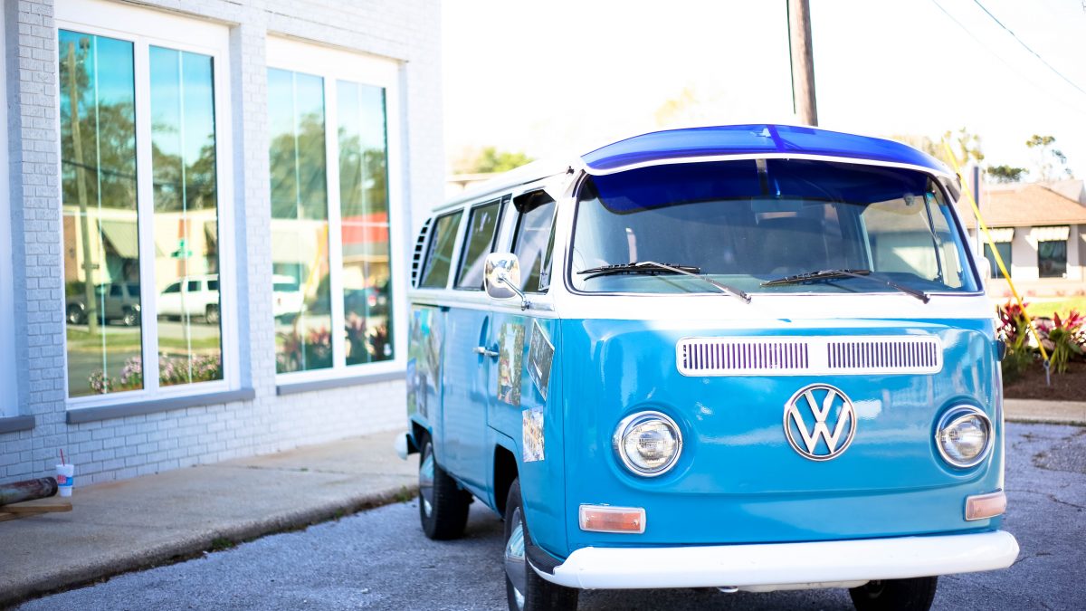 a bright blue VW camper parked in the sunshine