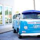 a bright blue VW camper parked in the sunshine