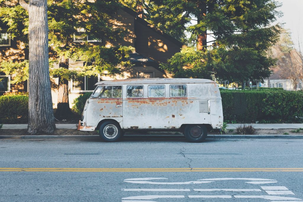 an old rusty grey campervan for sale parked on the side of a street