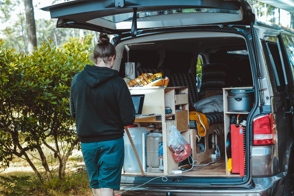 a woman works on a lamptop in the back of a converted campervan