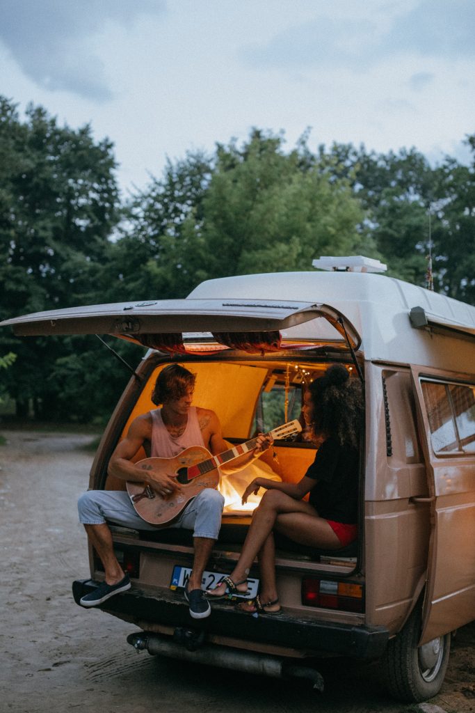 a couple sit in the back of a small converted camper van