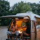 a couple sit in the back of a small converted camper van