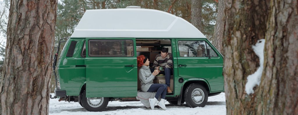 Green classic campervan in woods with snow