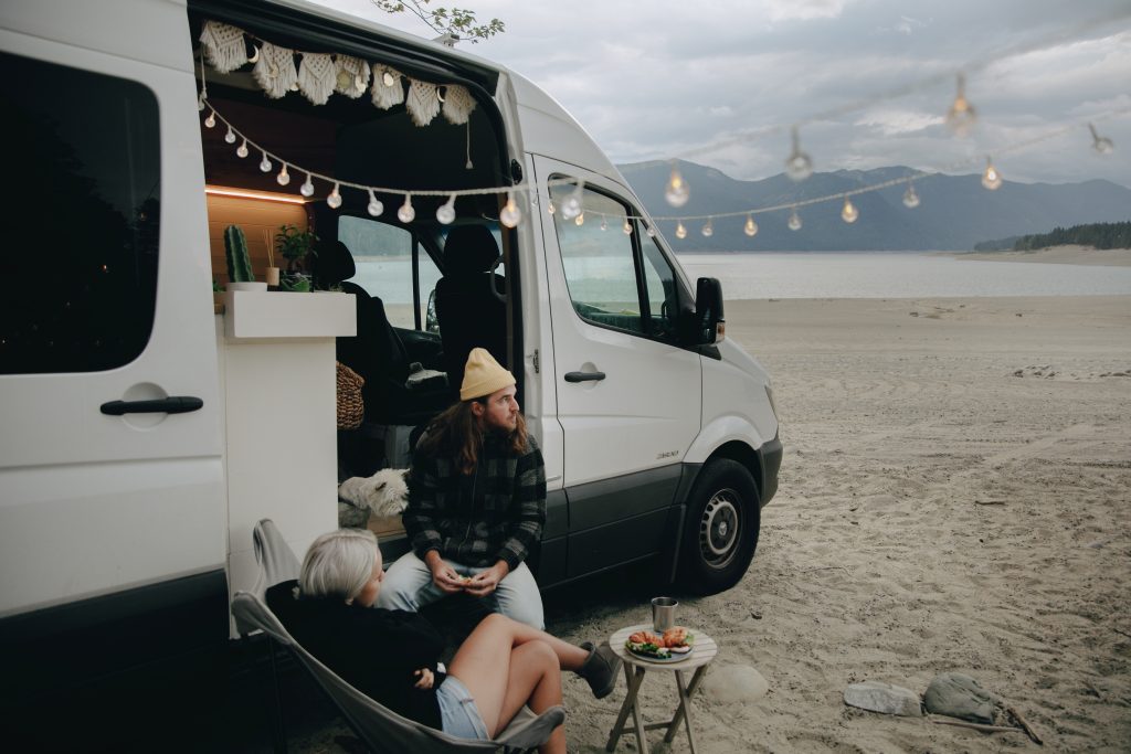 a couple sitting outside a white converted campervan