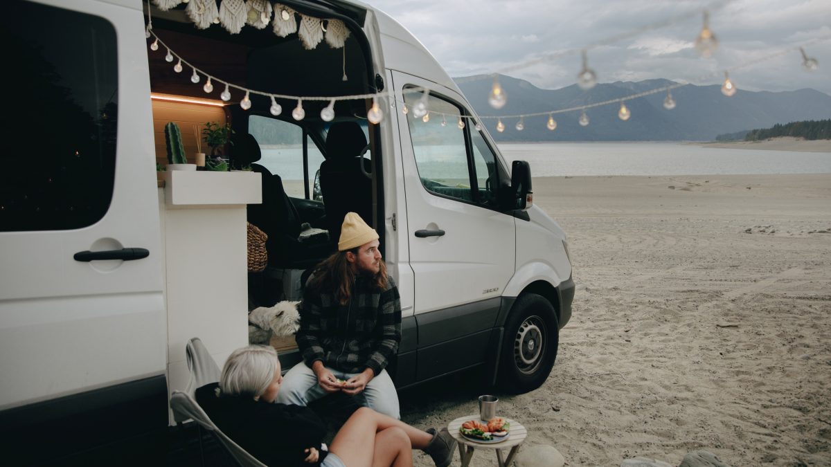 a couple sitting outside a white converted campervan