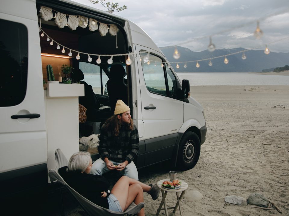 a couple sitting outside a white converted campervan