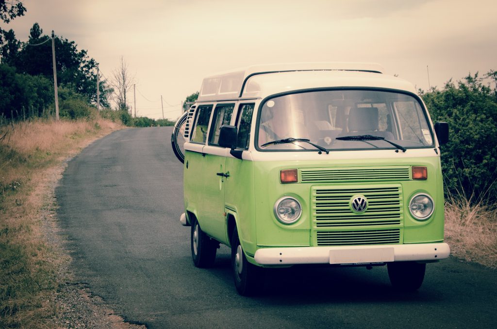 a pastel green VW campervan driving on a road