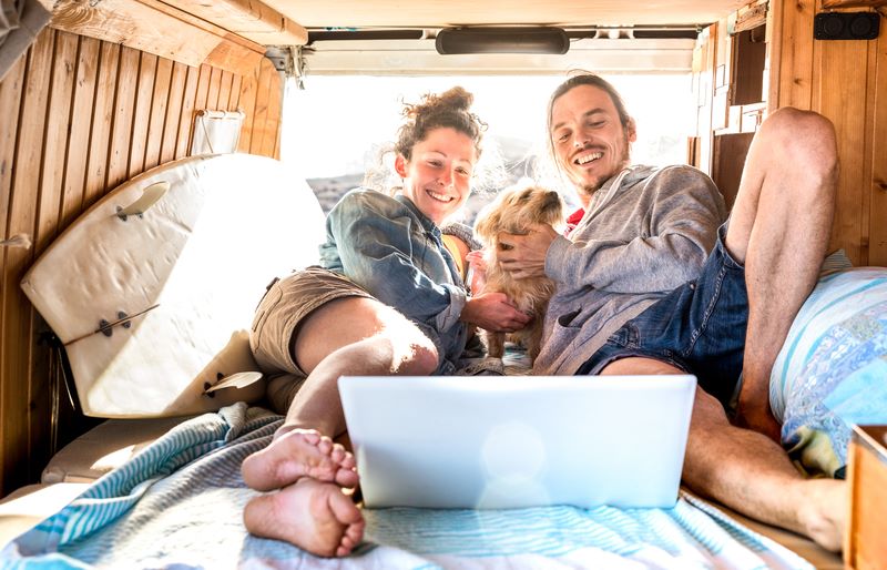 couple in campervan using laptop to look for campervan insurance probably