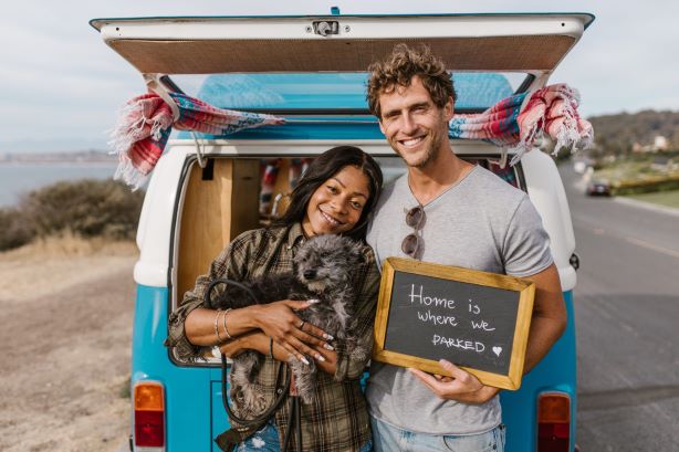 happy couple and dog standing at the back of a vw campervan